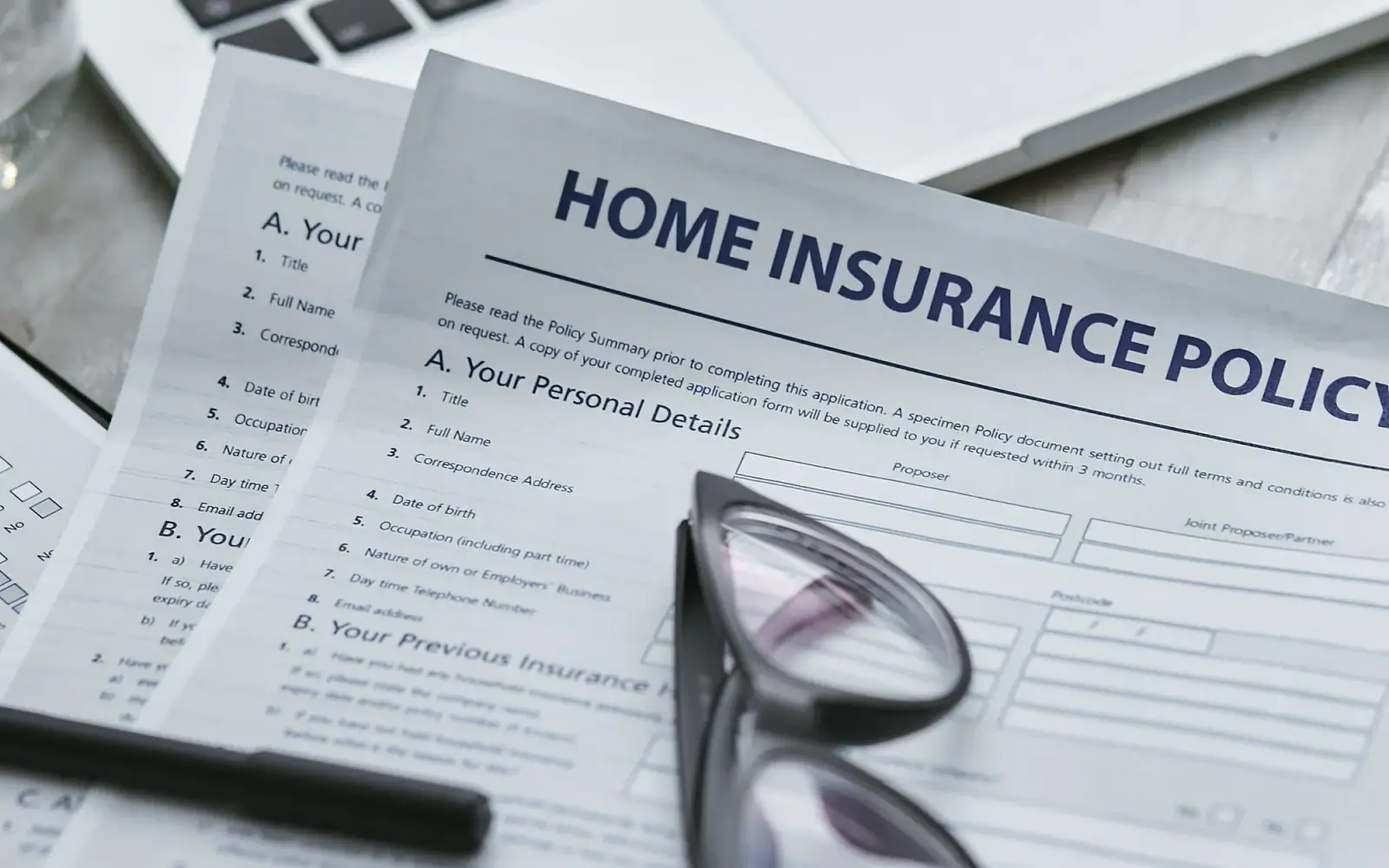 Home insurance policy documents reviewed beside a laptop